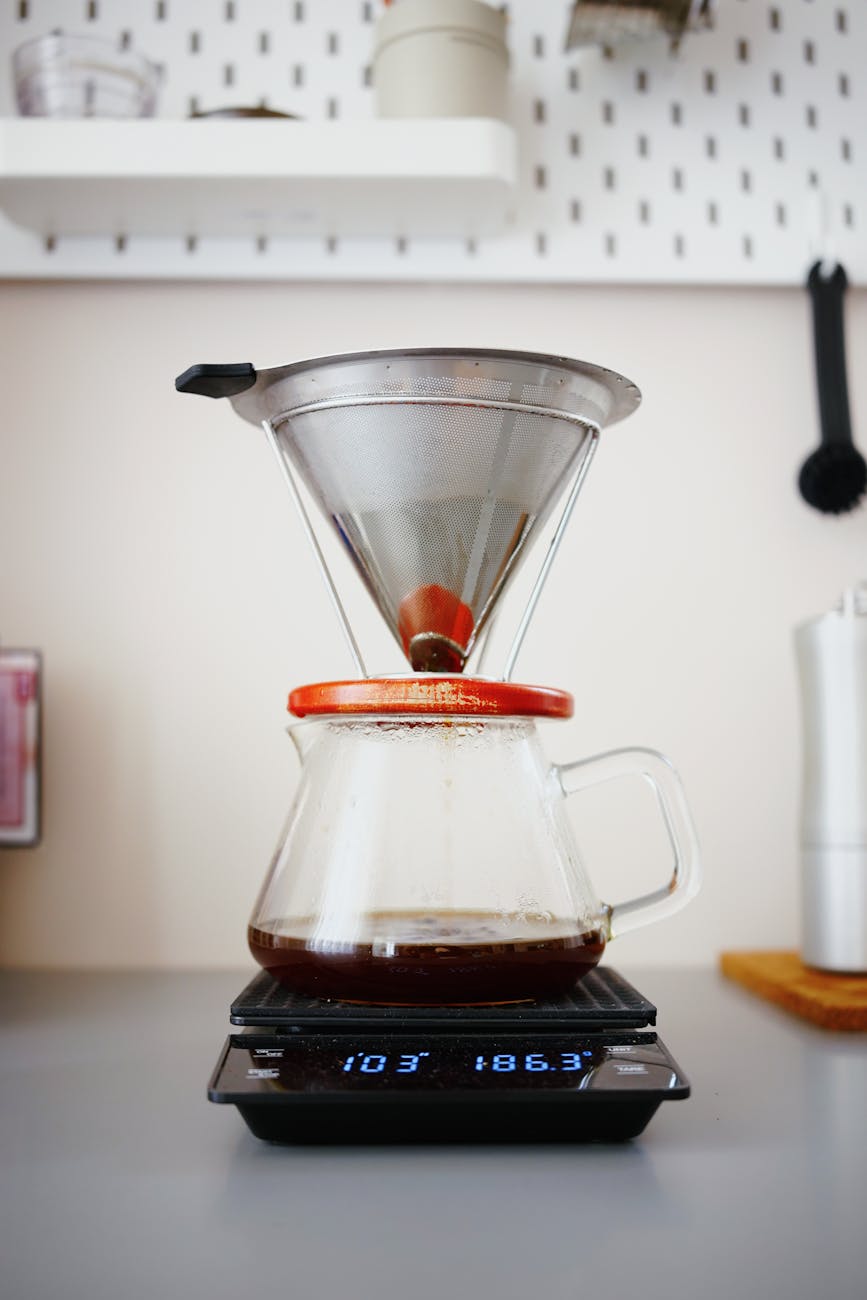 A beautifully organized home coffee bar setup featuring a premium coffee scale, a high-quality burr grinder, an elegant pour-over brewer, and freshly roasted coffee beans, demonstrating a complete brewing station, inviting atmosphere, warm tones