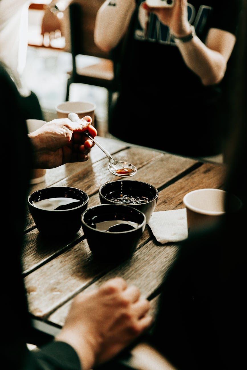 A close-up shot of a coffee tasting flight, with three cups of coffee brewed with different water types, showing a barista taking notes on flavor differences.