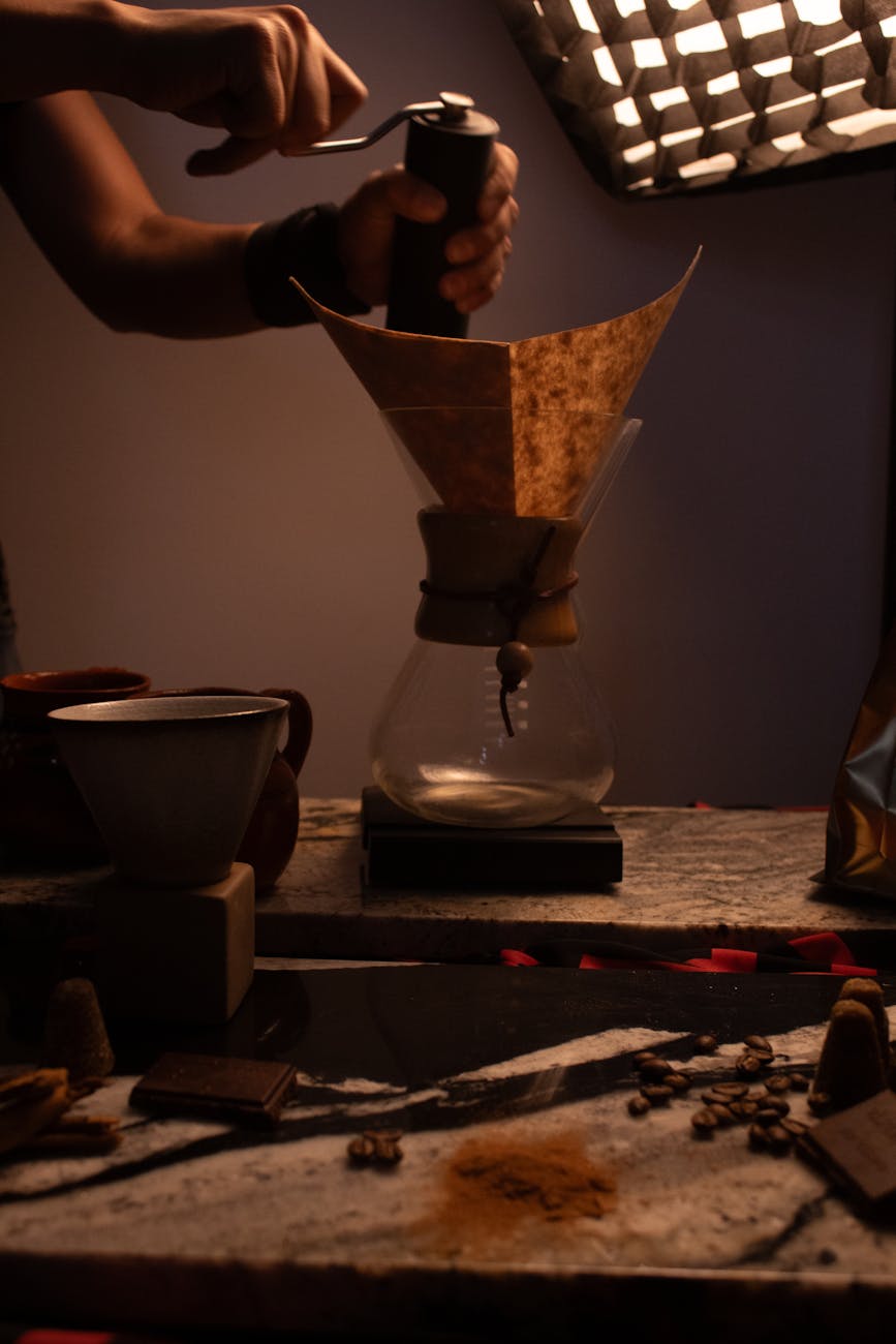 A coffee enthusiast setting up a pour over brew with a high-end coffee grinder in the background, showing attention to detail and precision.