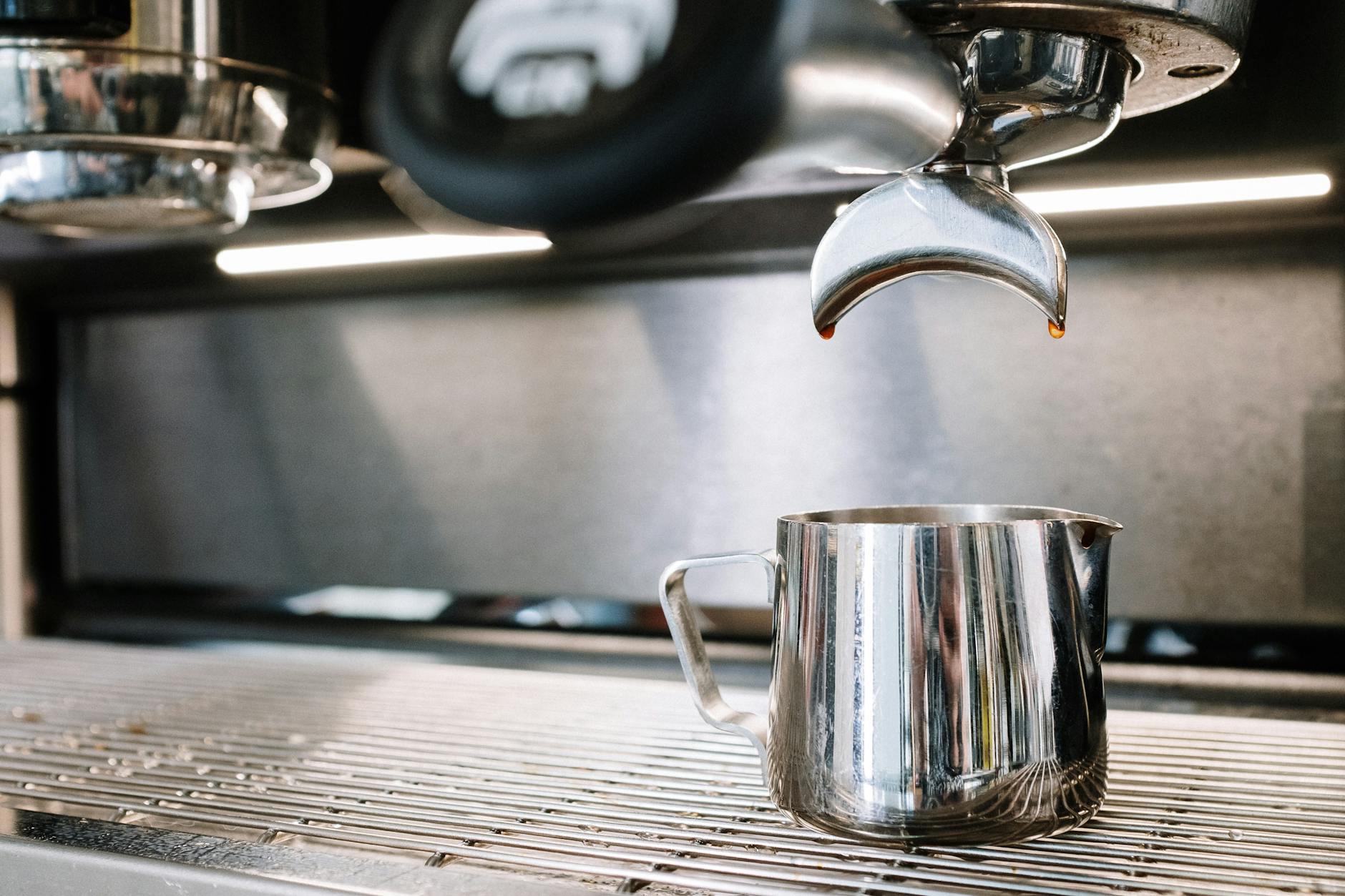 A modern drip coffee machine brewing coffee into a carafe, with steam rising and the kitchen bathed in morning light.