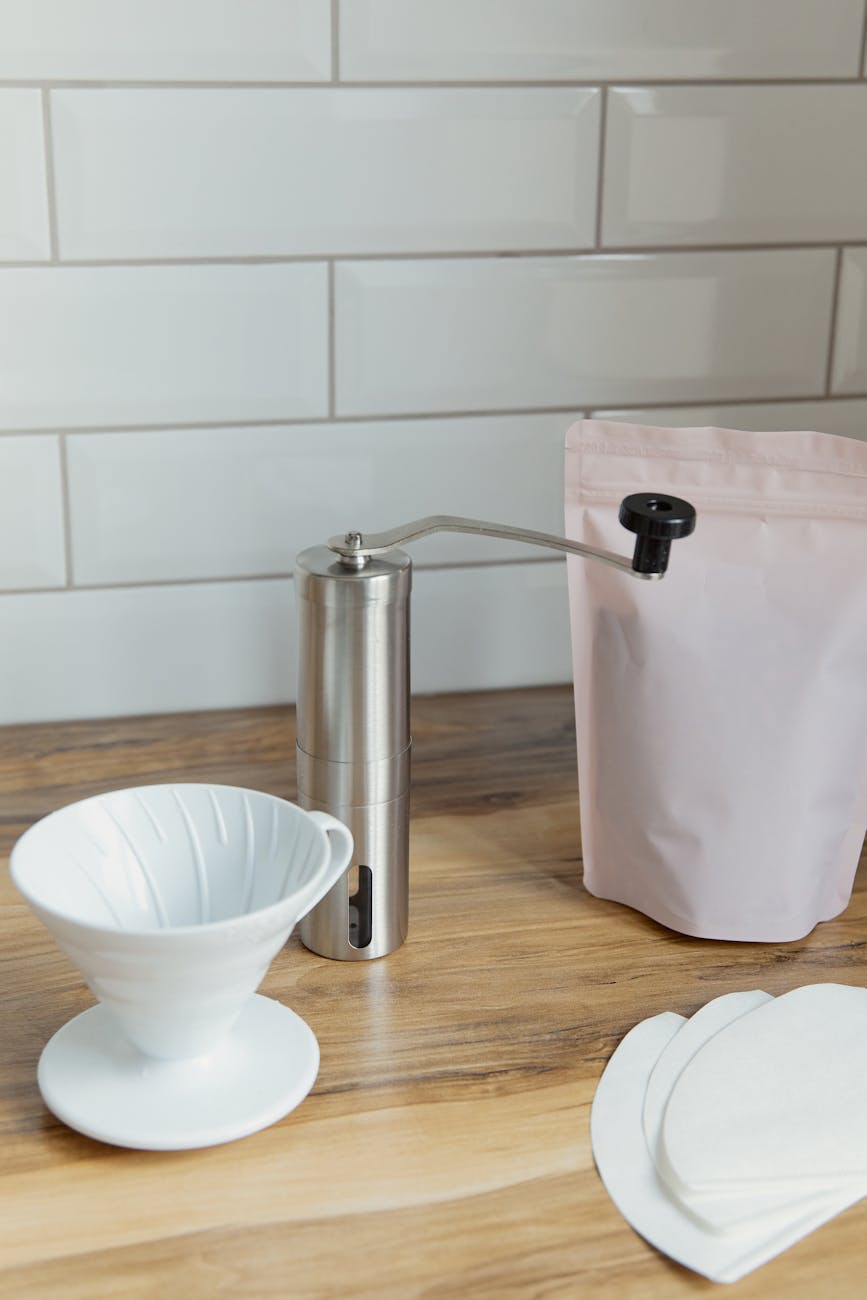 A stack of white paper coffee filters, clean and ready for use, next to a drip coffee maker filter basket.
